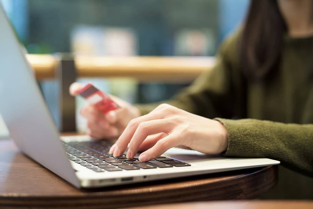Femme utilisant un ordinateur et sa carte de crédit pour effectuer une réservation en ligne. 